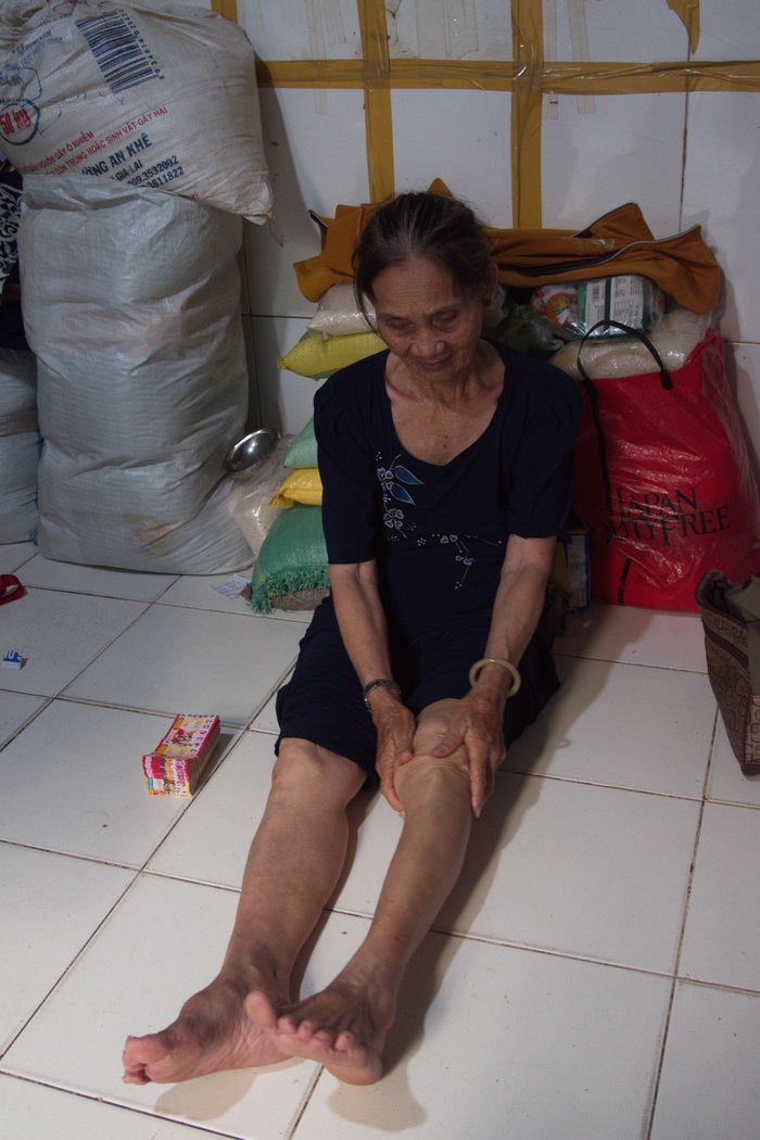Cô Năm tuổi ngoài 70 đang tranh thủ bóp chân cho đỡ đau trước khi lên đường bán tiếp vào buổi tối