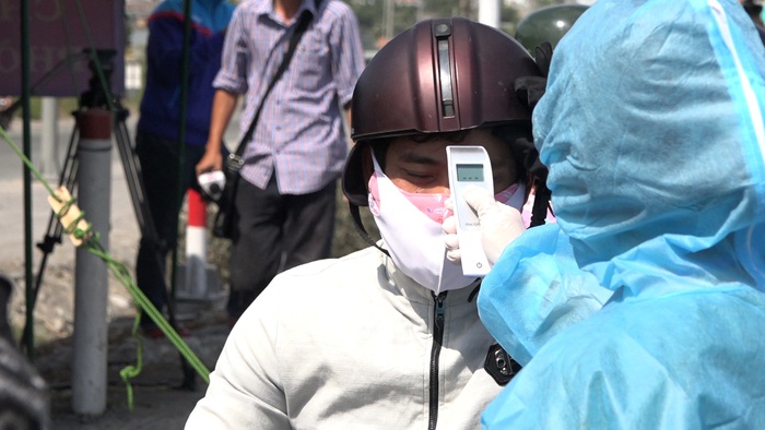 Nhân viên y tế tp Hồ Chí Minh đo thân nhiệt người đi mô tô từ Đồng Nai vào thành phố Hồ Chí Minh