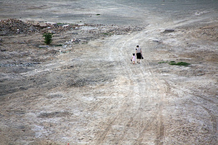Hai mẹ con dắt tay nhau đi trên con đường vắng ở Khiva (Uzbekistan).