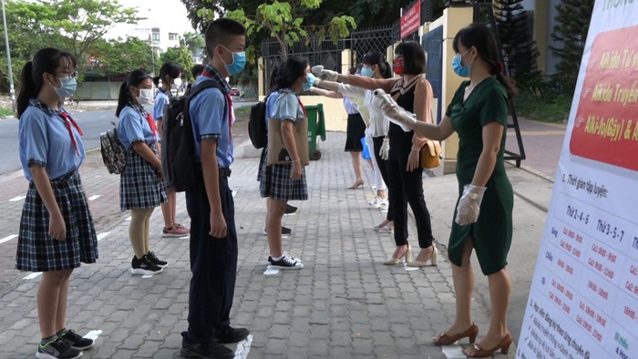 Học sinh Trường THCS Phạm Hữu Lầu (quận 7) đứng đúng vị trí cách nhau 1 mét để kiểm tra thân nhiệt trước khi được vào trường