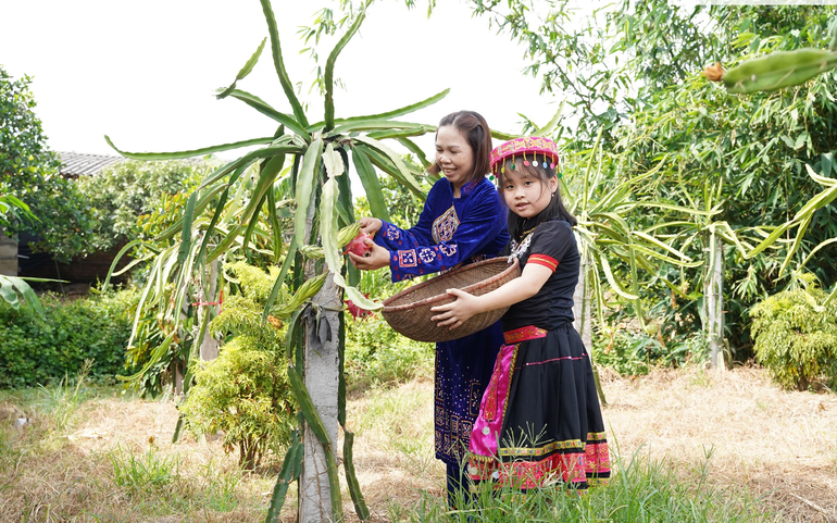 Chị Lã Thị Vương và con chăm sóc cây thanh long ruột đỏ của gia đình