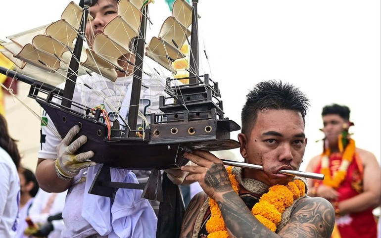 Một người sùng đạo với mô hình con tàu bị đâm qua má trong Lễ hội ăn chay Phuket. Ảnh: AFP.