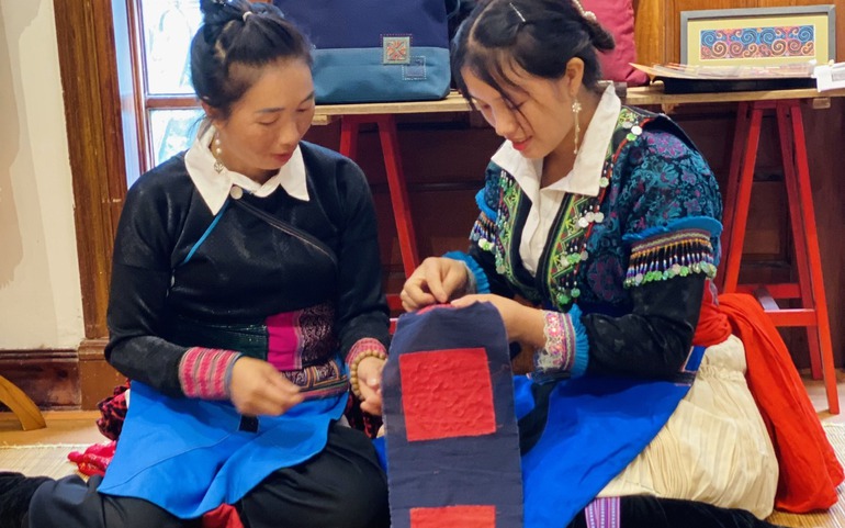 Nghệ nhân Sùng Thị Xé (trái) hướng dẫn kỹ thuật thêu của người H’Mông trắng. 