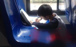 Bé 9 tuổi làm bài tập trên xe bus